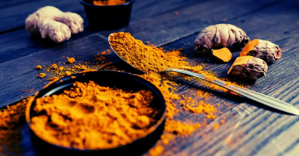 picture showing powdered turmeric in bowl with turmeric root next to the bowl